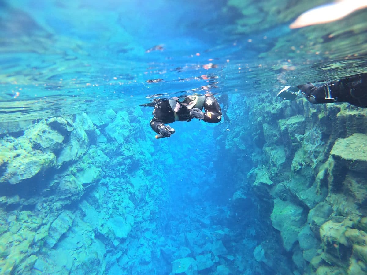 A snorkeller above a bright blue fissure